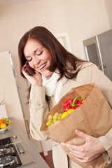 Smiling woman with mobile phone holding shopping bag