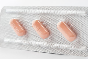 Closeup of a pack of three orange pills with selective focus