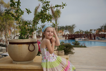 Fototapeta premium A little girl stands on the background of the pool