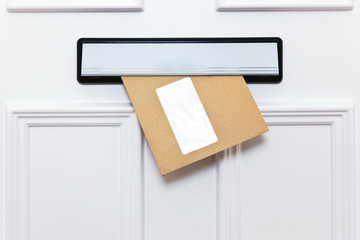 Brown envelope in a front door letterbox - 20618696