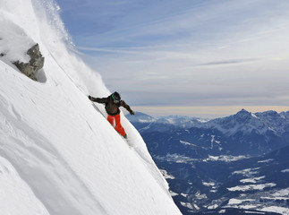 Snowboarder in einem steilen Tiefschneehang