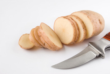 Sliced potato and knife over white background