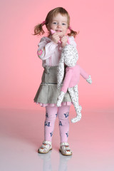 Little girl is playing with rabbit toy in studio