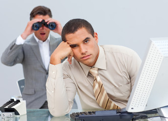 Handsome businessman getting bored and his manager looking throu