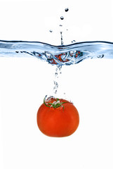 red tomato dropped into water isolated on white