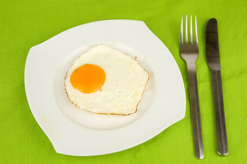 fried egg on a plate with a knife and a fork