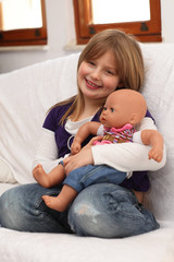 Fototapeta na wymiar Little girl with doll on sofa