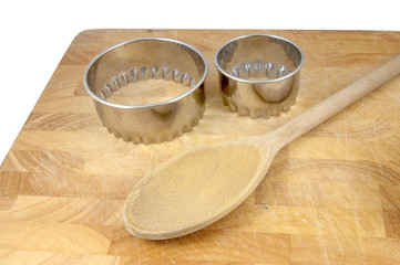 cookie cutters and wooden spoon on chopping board
