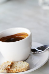 A cup of espresso with some biscuits by the side