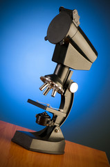 Microscope against blue gradient background