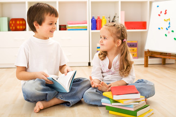 Fototapeta na wymiar School boy showing her little sister how to read