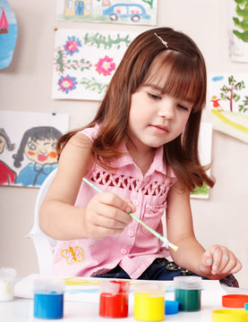 Child with picture and brush in play room. Preschooler.