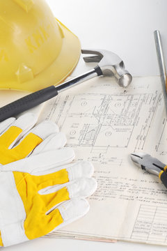 Yellow hardhat, gloves and hammer on drawings