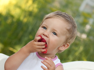 Baby is eating red raspberries