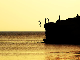 jumping of a cliff at sunset