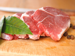 Raw pork chops on the cutting board. Peppers and bay leaves.