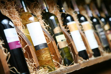 Closeup shot of wineshelf. Bottles lay over straw. - obrazy, fototapety, plakaty