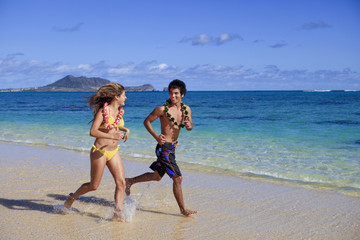 Fototapeta premium young couple running on the beach in hawaii