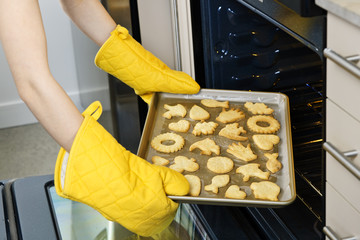 Taking cookies from oven - obrazy, fototapety, plakaty