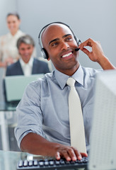 Cheerful businessman working at a computer with headset on