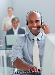 Ethnic businessman working at a computer with headset on