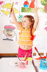 Child with picture and brush in play room. Prescooler.