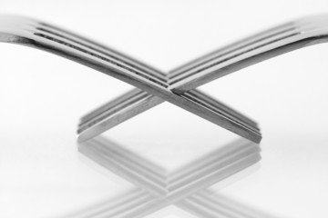 Two forks against a white background in black and white.