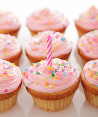 Lots of pink birthday cupcakes waiting to be enjoyed.