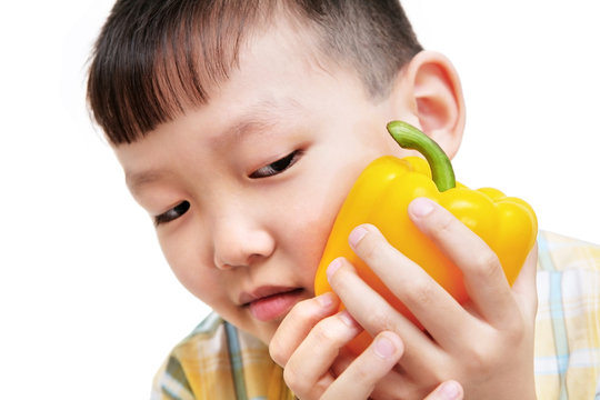 asian boy holding big yellow bell pepper