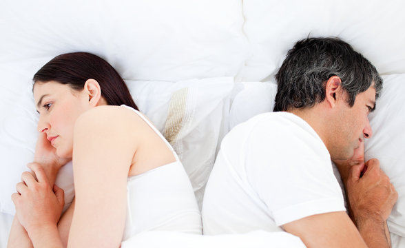 Upset couple sleeping in their bed separately
