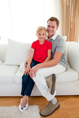 Obraz premium Blond little girl sitting on sofa with her father
