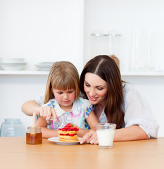 Obraz na płótnie Canvas Loving little girl and her mother having breakfast