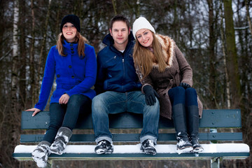 trio sitting on a parkbench in winter
