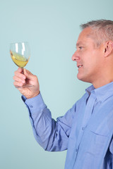 Man holding a glass of white wine checking it's clarity