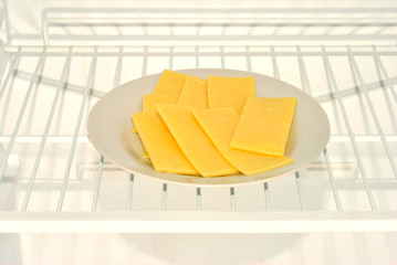 some slices cheese on a plate in a fridge
