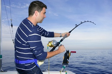 Angler fisherman fighting big fish rod and reel