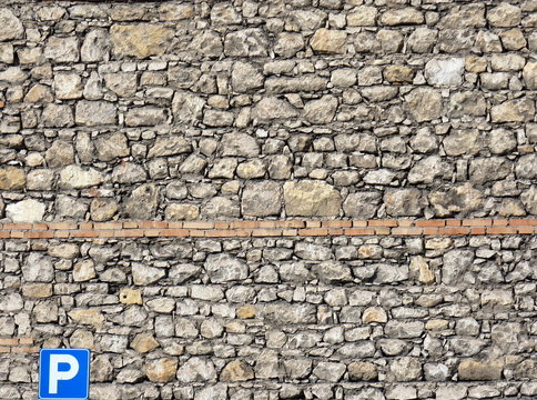 muro di pietre con cartello di parcheggio