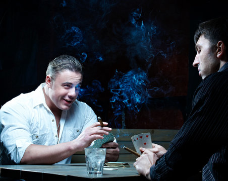 Two gamblers with cards smoking and drinking