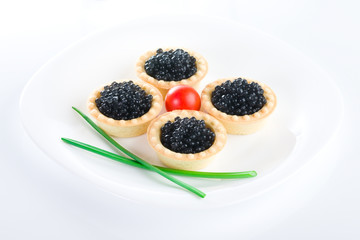 Tartlet with black caviar on a white platter