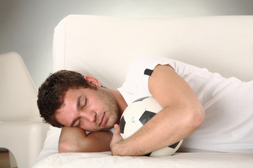 junger mann schläft mit seinem fussball sieger