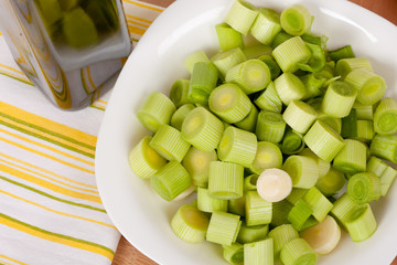 Fresh chopped leeks on a wooden board with red tomatoes