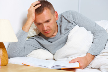 Obraz premium Sleepless man reading a book