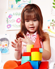 Child with wood block and construction set in play room.