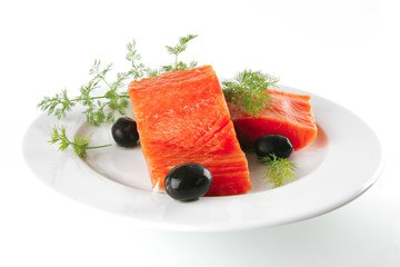 pink smoked salmon on white plate with olives