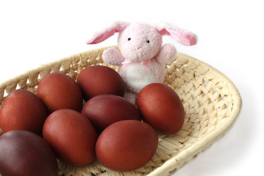 Red Easter eggs and the hare in a wicker tray