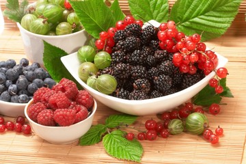 Berries in plates, on a table, among green leaves