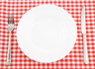 Waiting for meal, empty plate with knife and fork on tablecloth