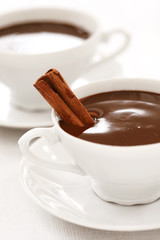 very chocolaty hot chocolate in white cups with cinnamon stick