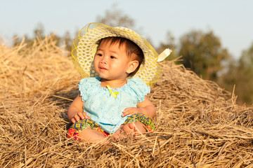 Naklejka na ściany i meble Baby von Asien sitzt auf Stroh