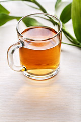 Cup of black tea and green leaves